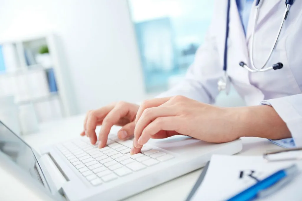 A doctor typing on a laptop.